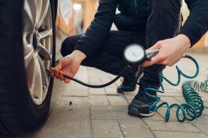 A man checking the tire pressure of a tire on his car.