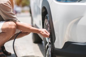 A man is inflating one of the tires on his car.