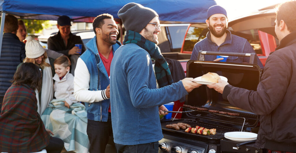 A group of friends enjoying a tailgate BBQ, grilling food and socializing before a game.