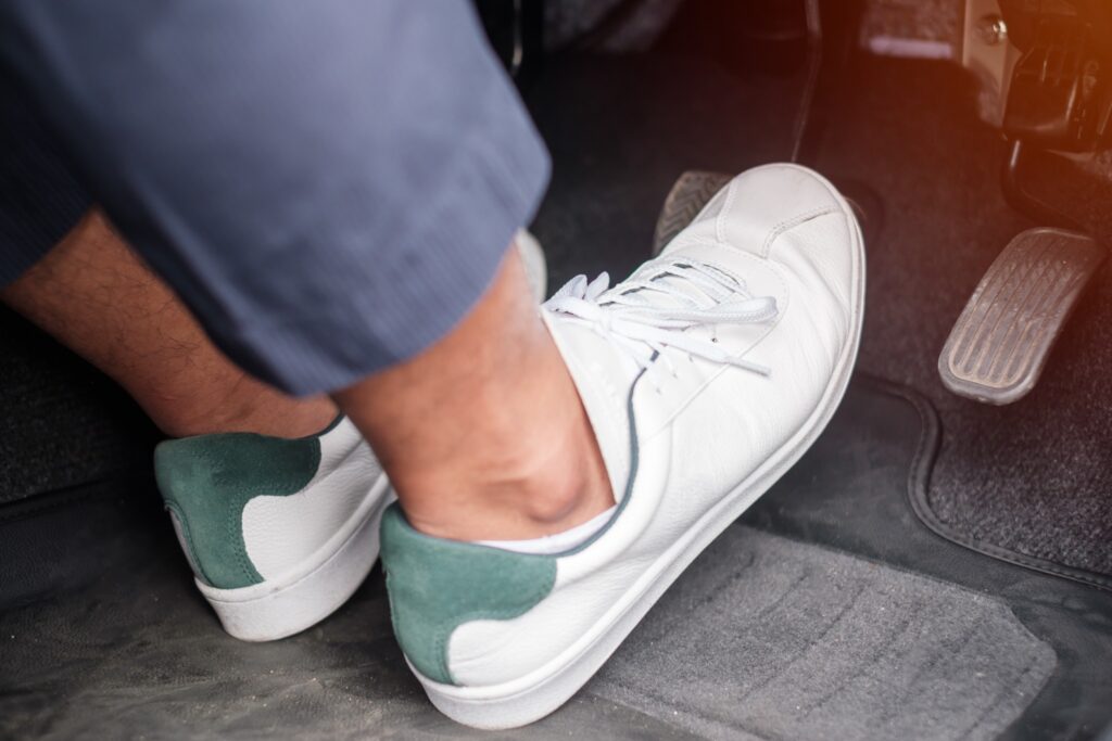 A driver’s foot presses down on a car pedal, emphasizing the importance of brake checks and safe driving habits for spring travel.