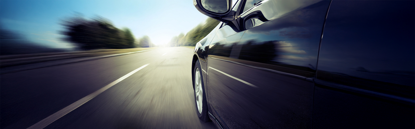 A close-up of a black car driving down a clear open road, symbolizing forward momentum and flexibility—used as a header image for a leasing-focused blog by Fusion Auto Finance.